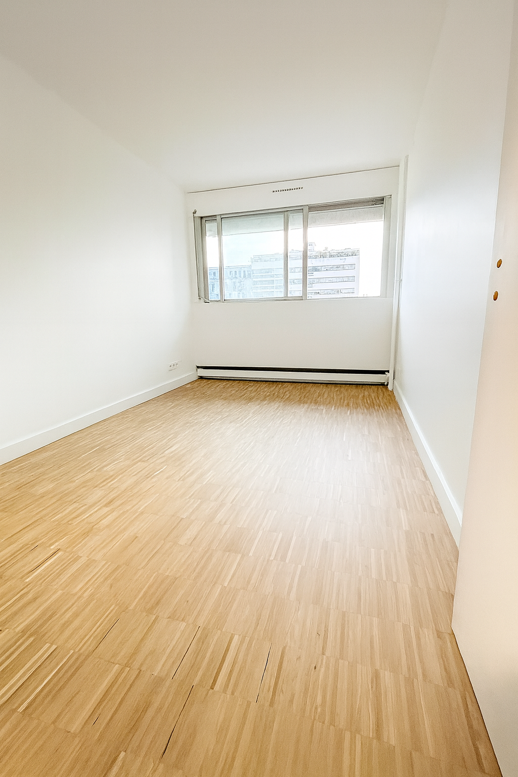 Chambre rénovée à Paris avec parquet sur chant et murs peints en blanc – rénovation intérieure MAKRENO