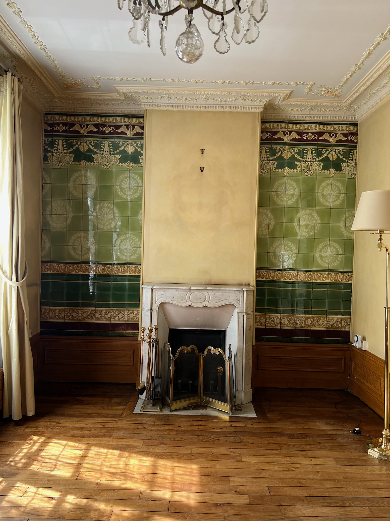 Séjour d’une maison de style château à Enghien-les-Bains avant rénovation – cheminée en marbre, boiseries d’origine et faïences murales vertes