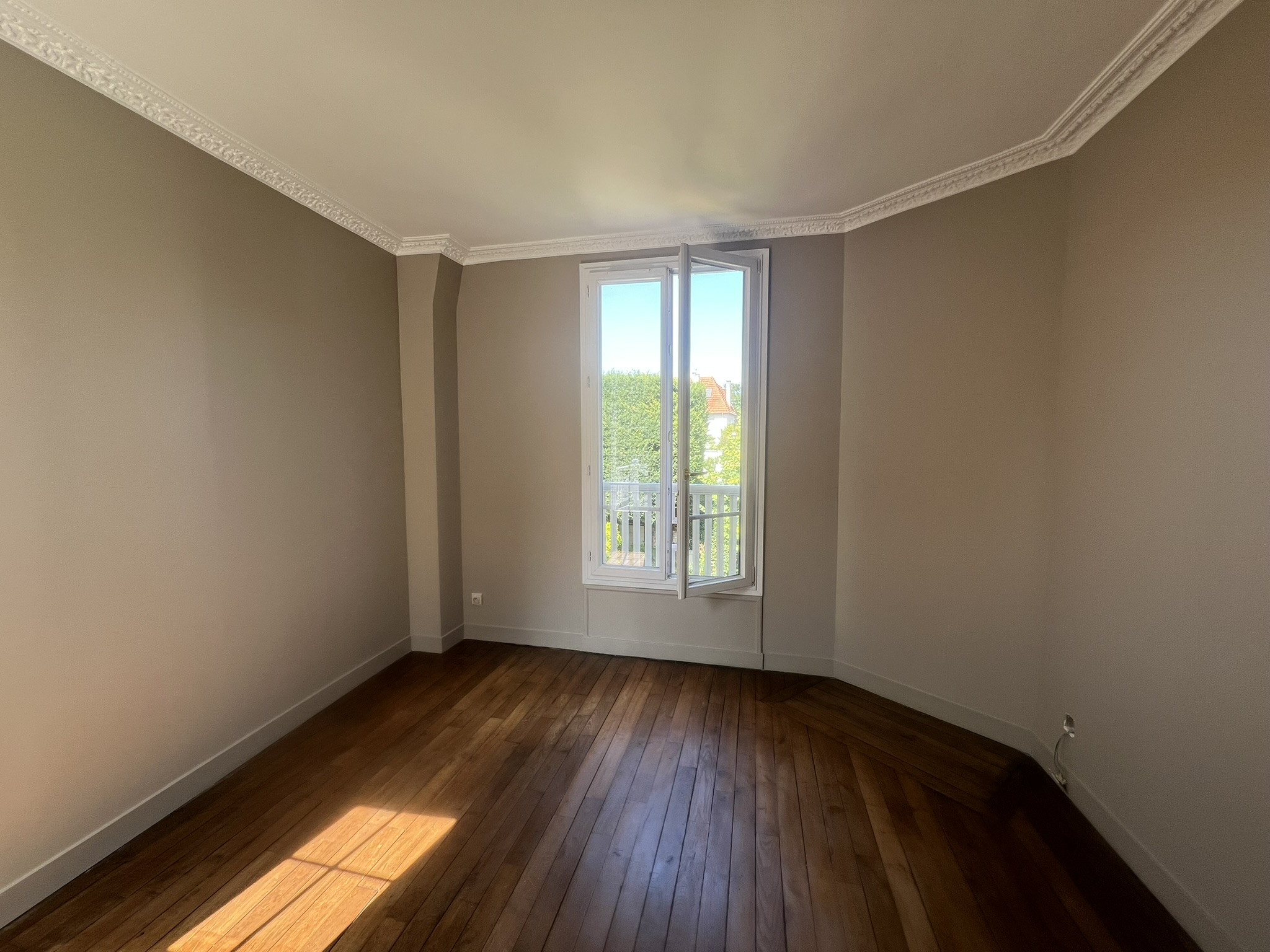 Chambre rénovée d’une maison de style château à Enghien-les-Bains – murs peints dans une teinte douce taupe, moulures restaurées et parquet ancien remis en valeur