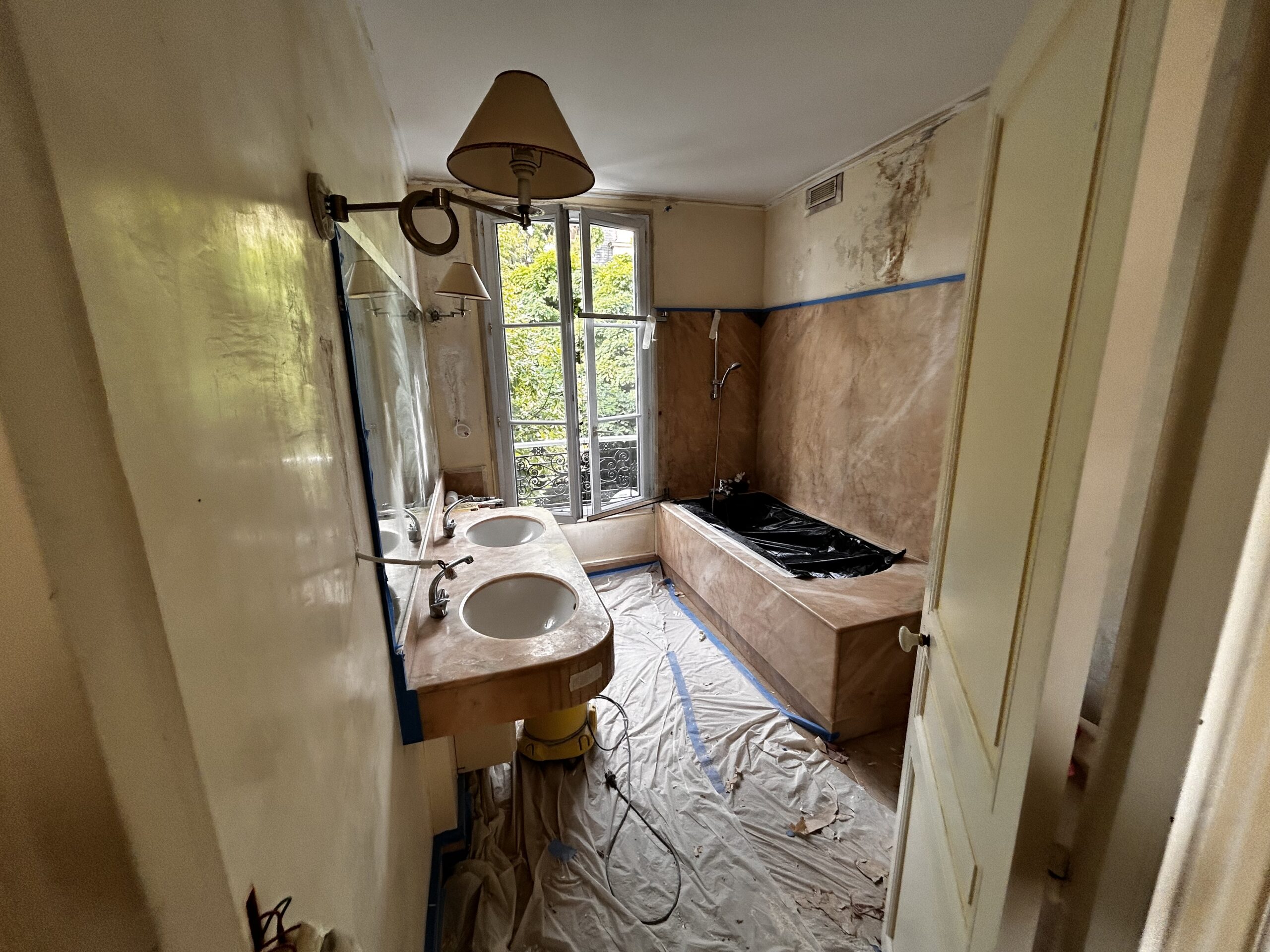 Salle de bain avant rénovation dans une maison de style château à Enghien-les-Bains – murs abîmés, plafond jauni et mobilier ancien avant reprise complète