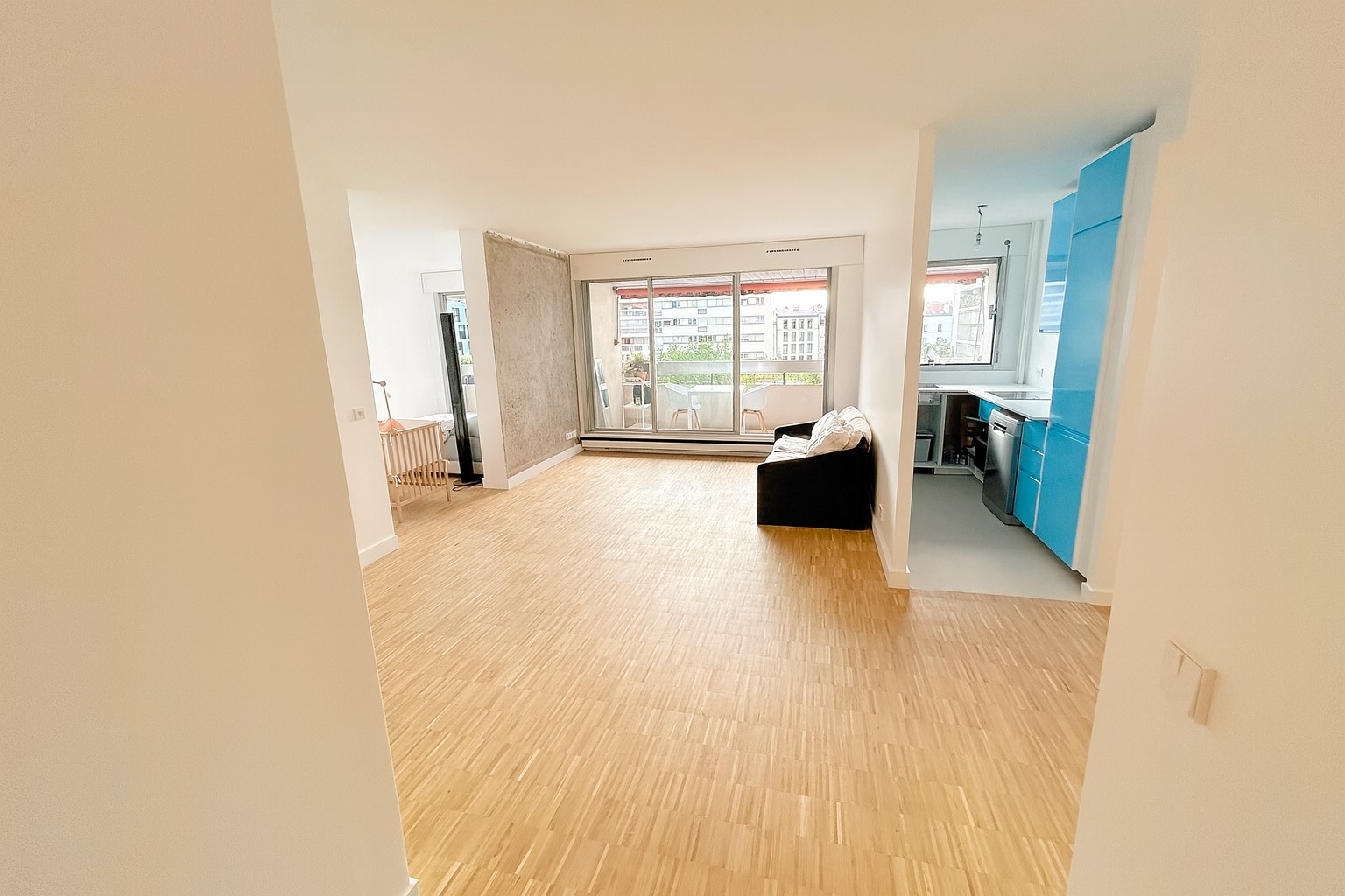 Salon rénové à Paris avec parquet sur chant et cuisine ouverte bleue – rénovation intérieure MAKRENO